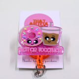 A pink badge reel with glitter showcasing a smiley donut and coffee cup, adorned with the phrase 