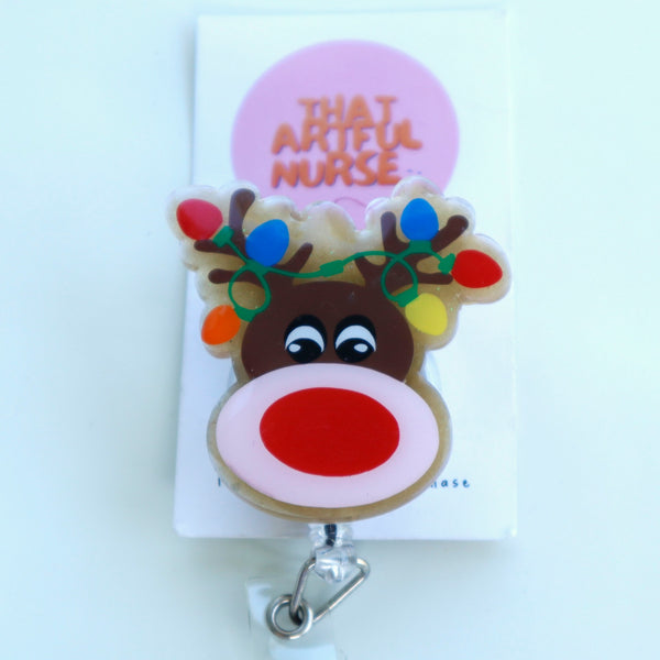 Acrylic Christmas reindeer badge reel with glitter finish, red nose, and colorful lights on antlers.
