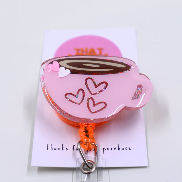 A charming pink expresso coffee cup with hearts, featured on a badge reel. Perfect for valentine's day.