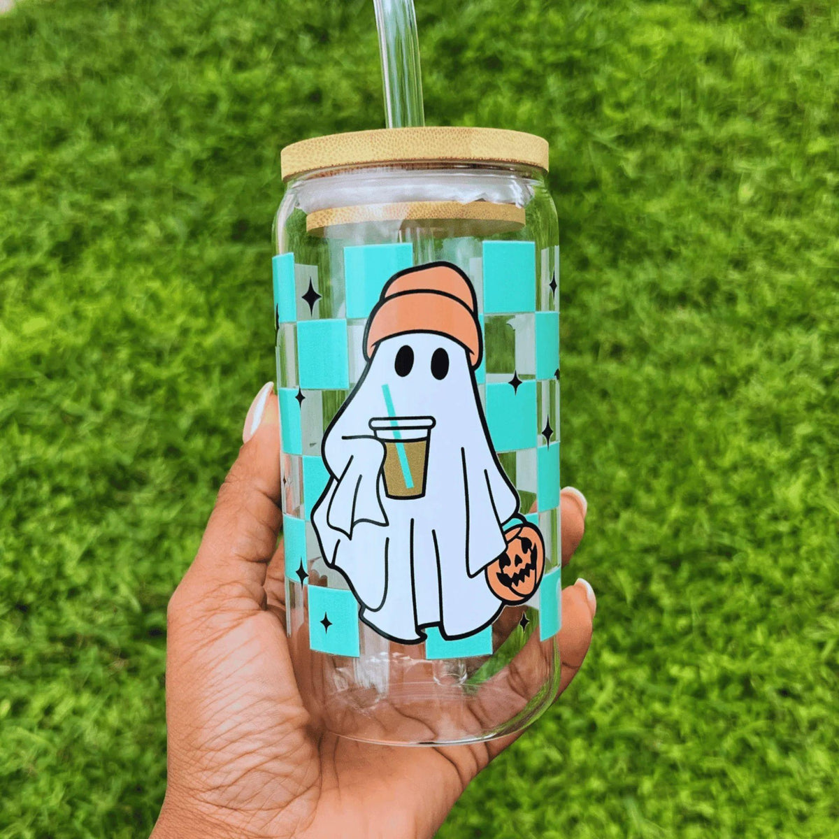 Clear glass can-style cup featuring a playful ghost and a turquoise checkered pattern with bats, complete with a reusable straw—perfect for spooky season.