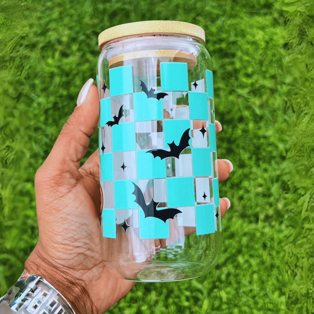Clear glass can-style cup featuring a playful ghost and a turquoise checkered pattern with bats, complete with a reusable straw—perfect for spooky season.