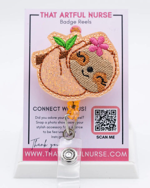 Lazy Daze - peach glitter embroidered sloth badge reel featuring smiling face hanging from branch with pink flower for nurses and professionals.