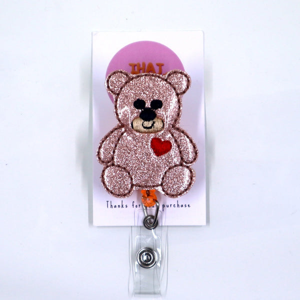 Glittery teddy bear badge holder with a pink heart on a white background