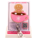 Pink glitter mug badge reel with a smiling gingerbread man in hot cocoa, featuring a white snowflake design and retractable clip.