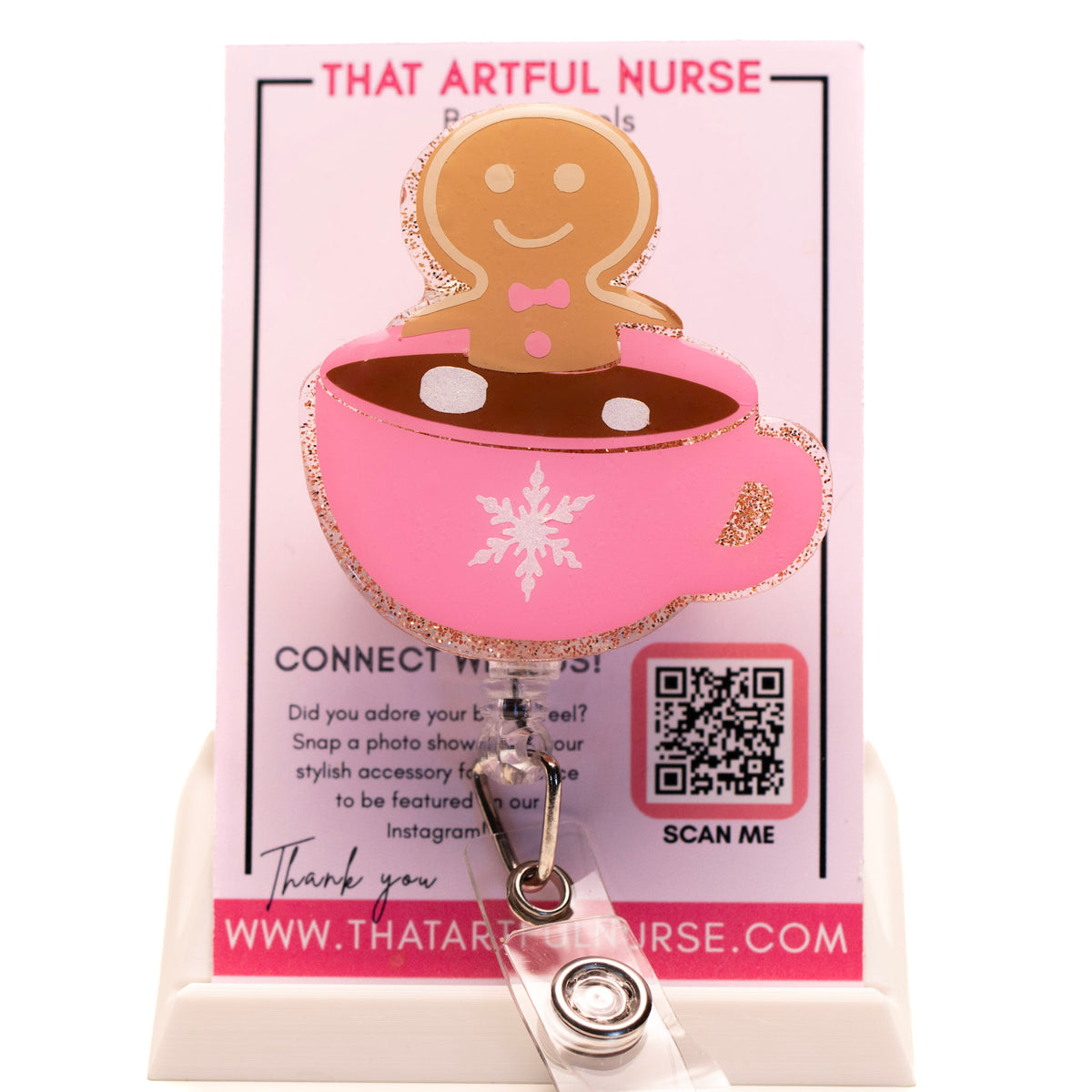 Pink glitter mug badge reel with a smiling gingerbread man in hot cocoa, featuring a white snowflake design and retractable clip.