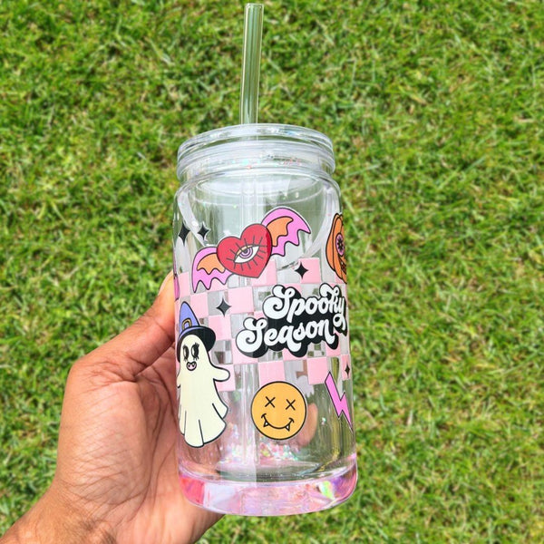 16oz snow globe tumbler featuring a vibrant collage of retro-inspired Halloween icons—from groovy ghosts to winged eyeballs and lightning bolts—all dancing around the bold “Spooky Season” slogan