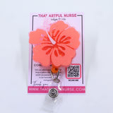 Pink hibiscus flower badge reel from That Artful Nurse displayed on a branded card.