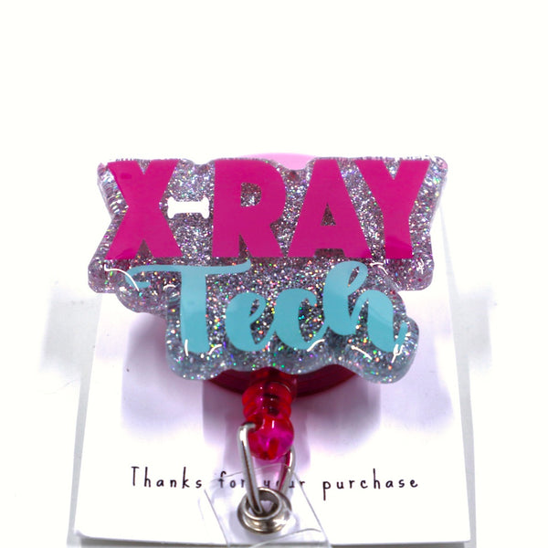 A glittery badge reel with the words "X-RAY Tech" in pink and light blue,