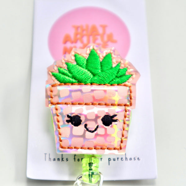 A cheerful little plant with a smiley face, attached to a badge reel.
