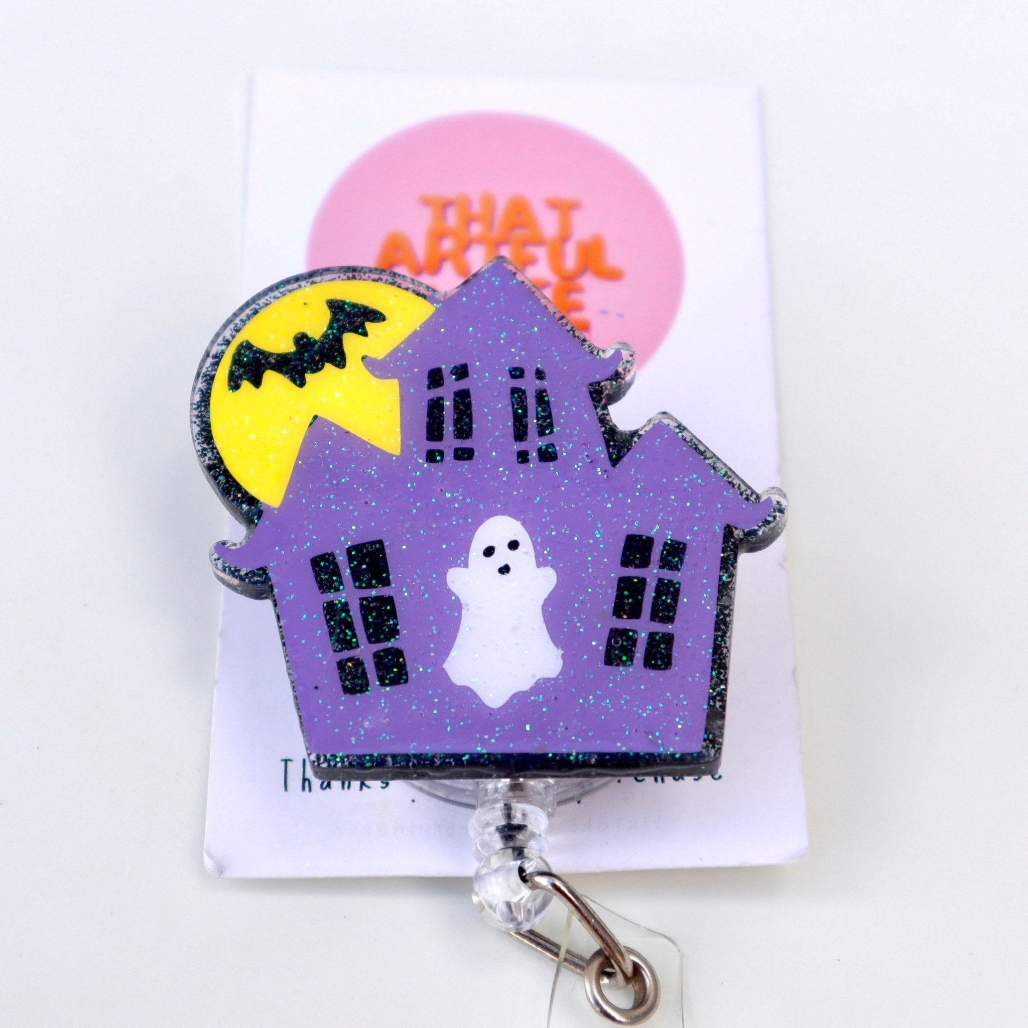 A badge reel featuring a purple haunted house with a ghost and a full moon in the background.